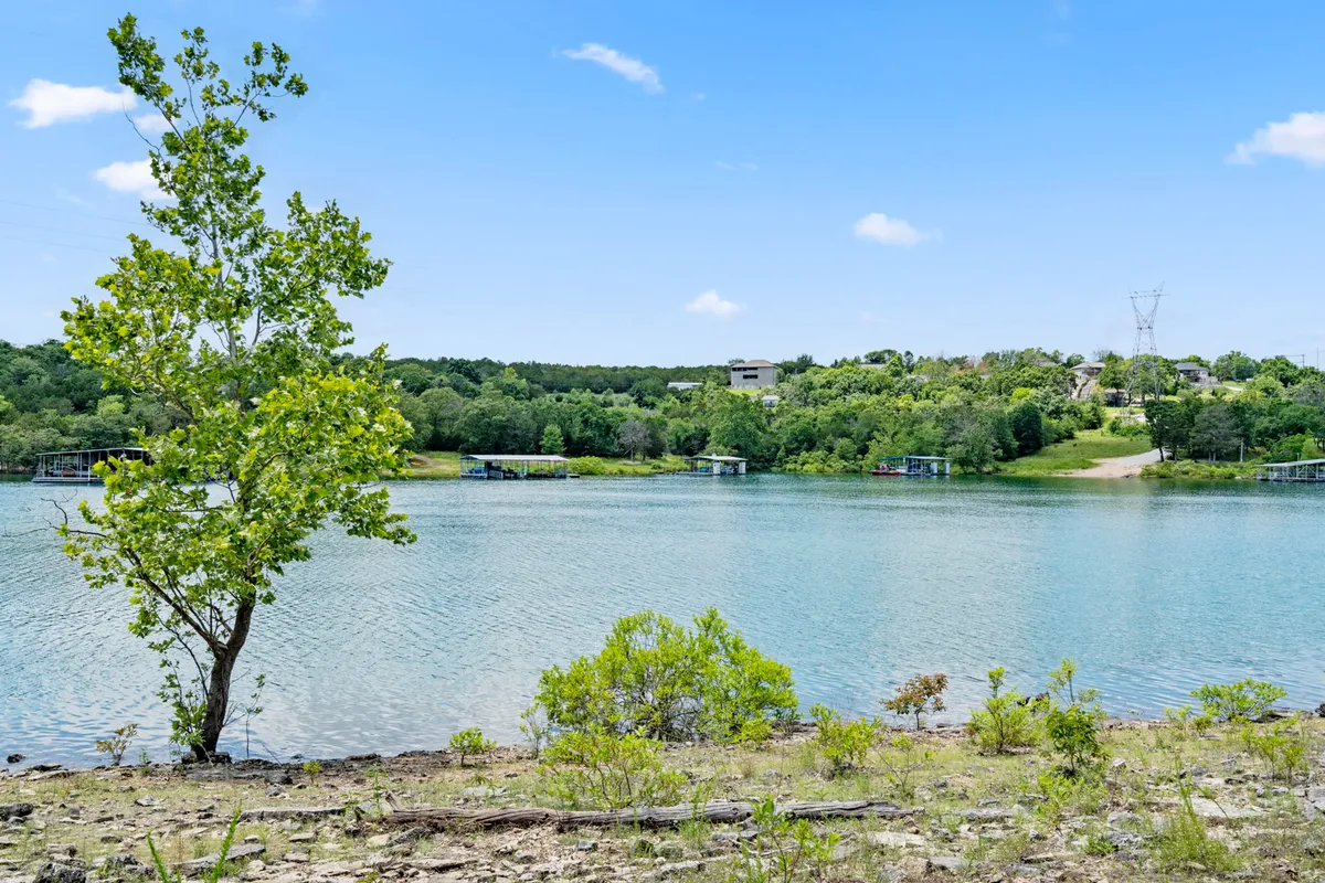 The image features a tranquil view of Table Rock Lake, with the calm water framed by trees and distant buildings visible on the shoreline. The soft golden light suggests a sunset or sunrise, evoking peace and a deep connection to nature.