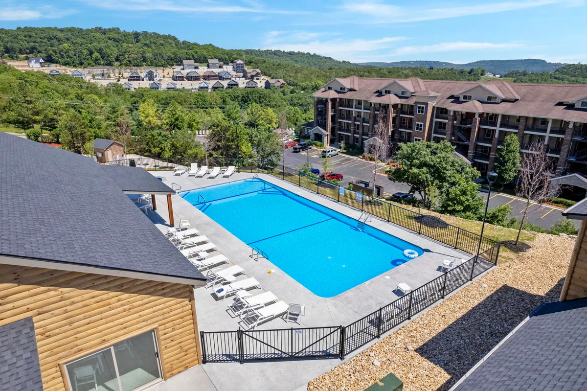 An inviting outdoor swimming pool surrounded by lounge chairs, set against a scenic landscape. The pool area is bright, open, and perfect for families to gather, splash, and relax. The view from the pool deck highlights the natural beauty of the resort's setting.