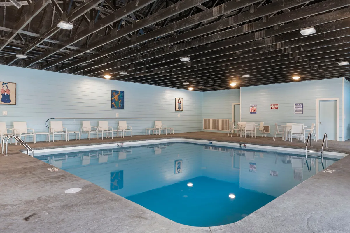 A cheerful indoor swimming pool area featuring vibrant artwork on the walls, cozy seating, and abundant natural light filtering through large windows. The space feels bright, fun, and welcoming for year-round aquatic enjoyment.