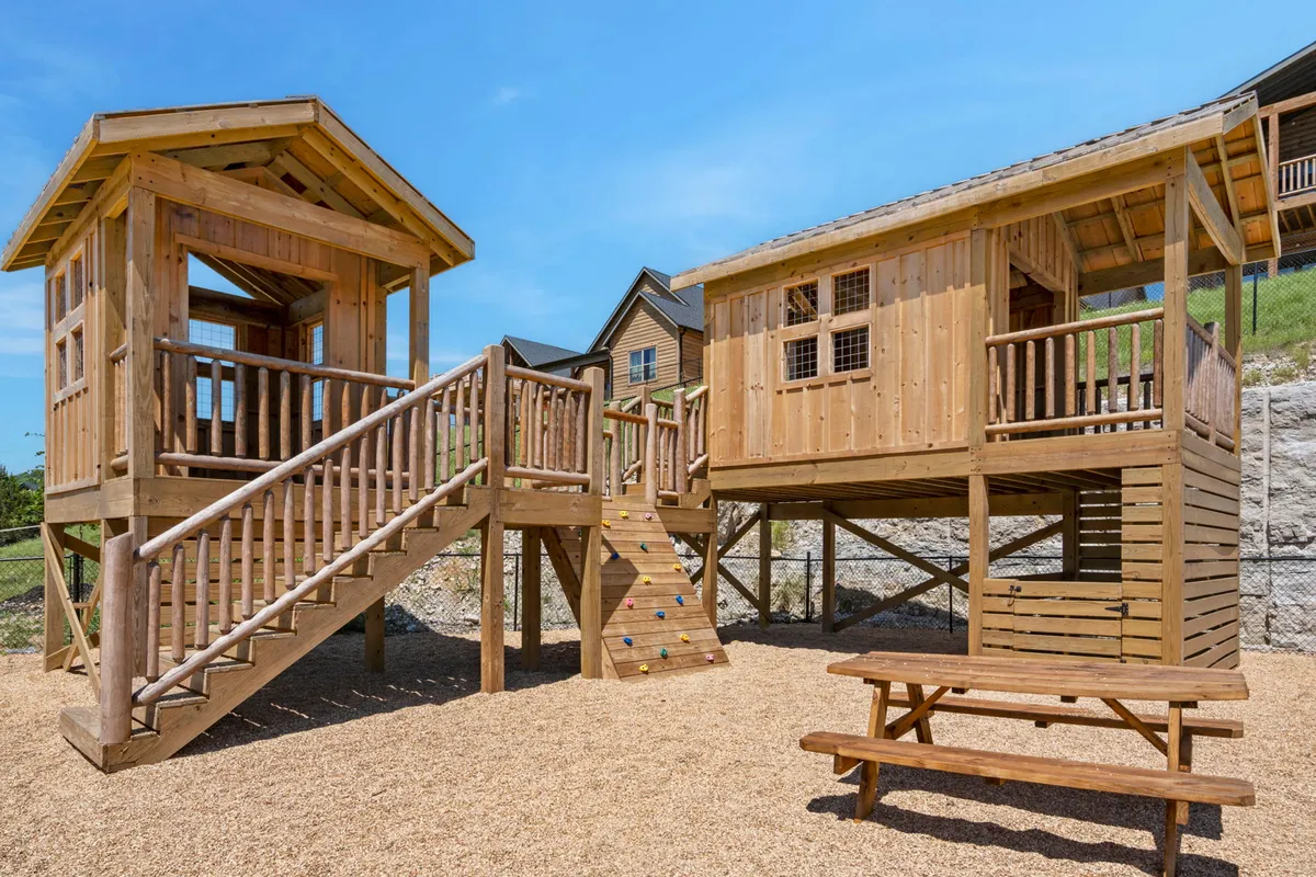 A colorful playground with multiple play structures, stairs, a climbing wall, and a picnic table, set outdoors to capture the vibrant mood of joyful family playtime and friendly social gatherings.