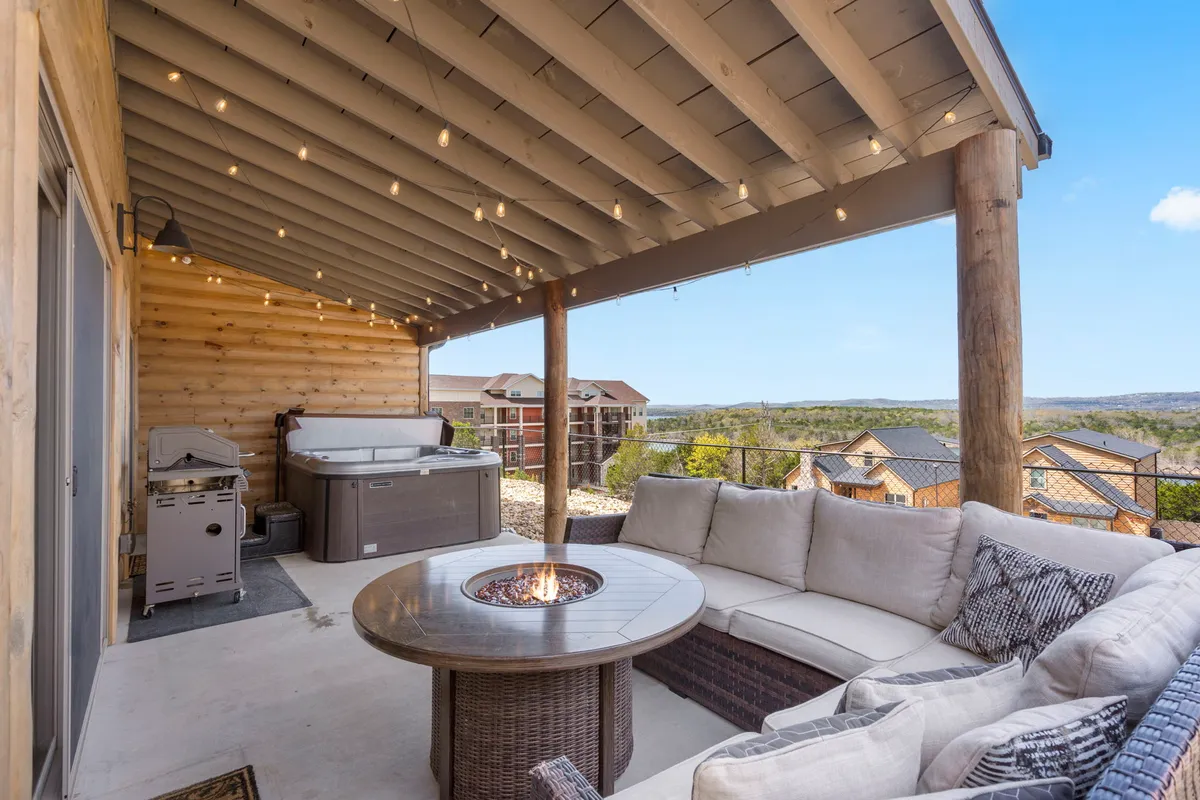 This image showcases a serene outdoor area with a hot tub, cozy seating, a fire pit, and stunning mountain views. String lights add a magical touch, contributing to an intimate atmosphere ideal for evening relaxation or celebrations. The scene is inviting and peaceful, perfect for couples or small groups seeking a memorable escape.